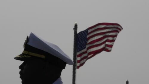 Cmdr. Executive Officer Tyrchra Bowman stand in front of U.S flag on the missile destroyer USS Arleigh Burke, docked in the port in southern city of Limassol, Cyprus, Wednesday, May 17, 2023. (AP Photo/Petros Karadjias)